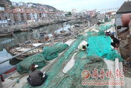 渔民在码头修补渔网准备休渔期