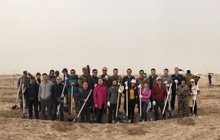 一群年轻人在沙漠中合影植树