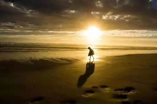 女生在夕阳下看着手机微笑