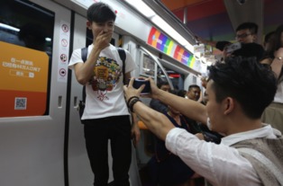 地铁站内一位男士尴尬地看着另一位男士的手