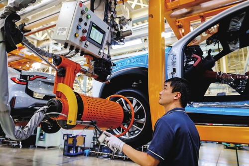 电动汽车生产线上的工人操作机械臂安装电池组