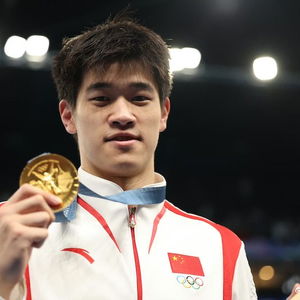 潘展乐站在领奖台上高举双手庆祝