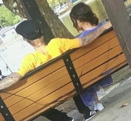 两人并肩坐在公园长椅上看夕阳