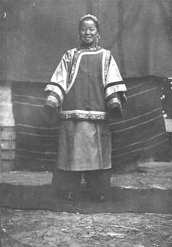 李明身着传统清朝服饰与古董摆件合影