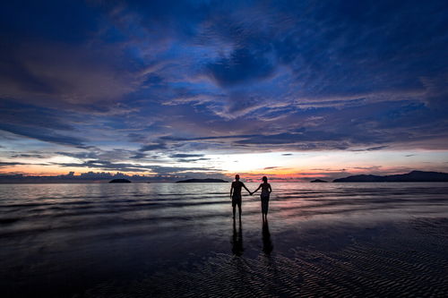 两个人手牵手走在海边