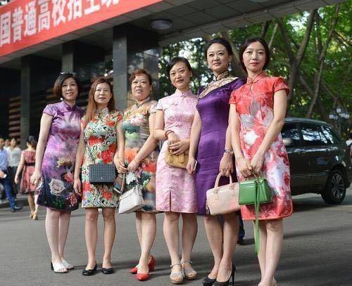 多位家长身穿各色旗袍在校门口合影