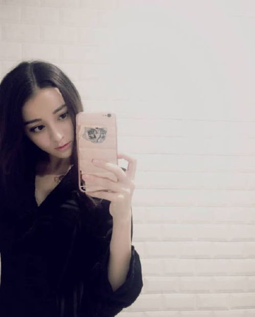 女生拿着手机在镜子前自拍