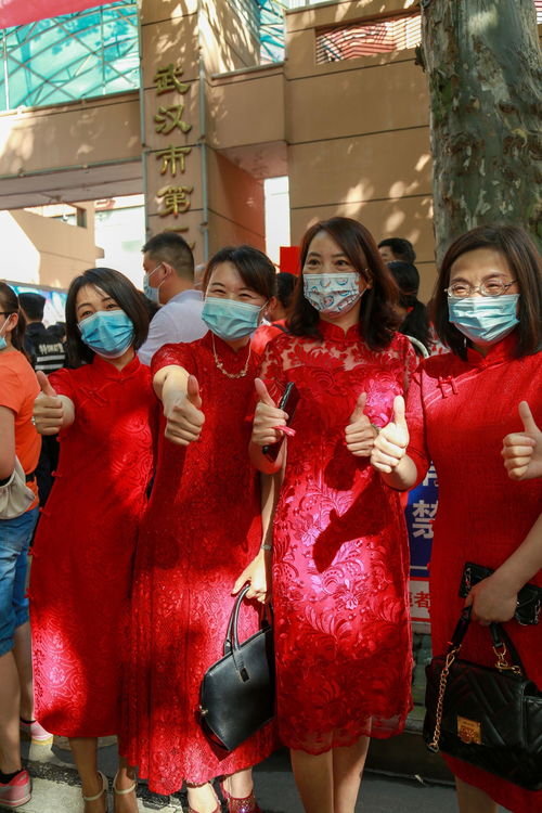 多位家长身穿红色旗袍在校门口合影