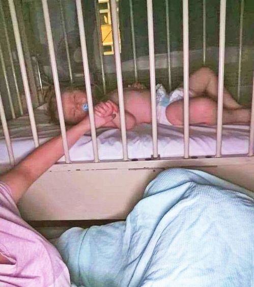 母亲在病床前握着孩子的手