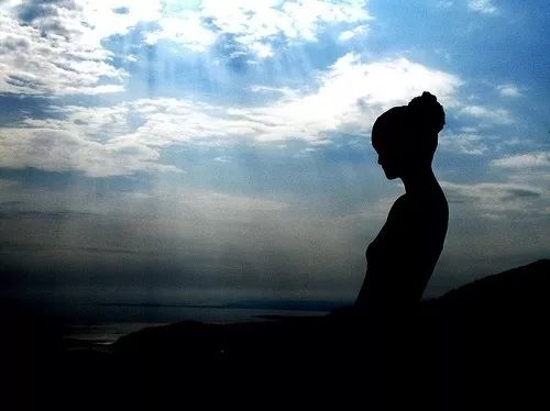 一位女性站在窗前凝视远方沉思