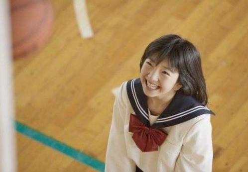 学生站在窗边阳光洒落脸上微笑