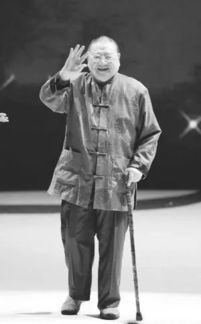 倪匡坐在书桌前写字的照片