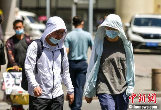 市民佩戴遮阳帽和口罩在高温下出行
