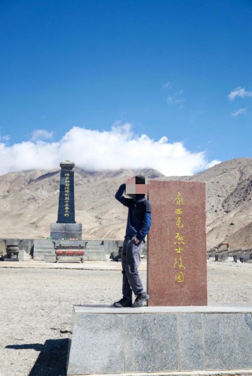 一个人手捧逝者的遗物站在墓碑前沉思