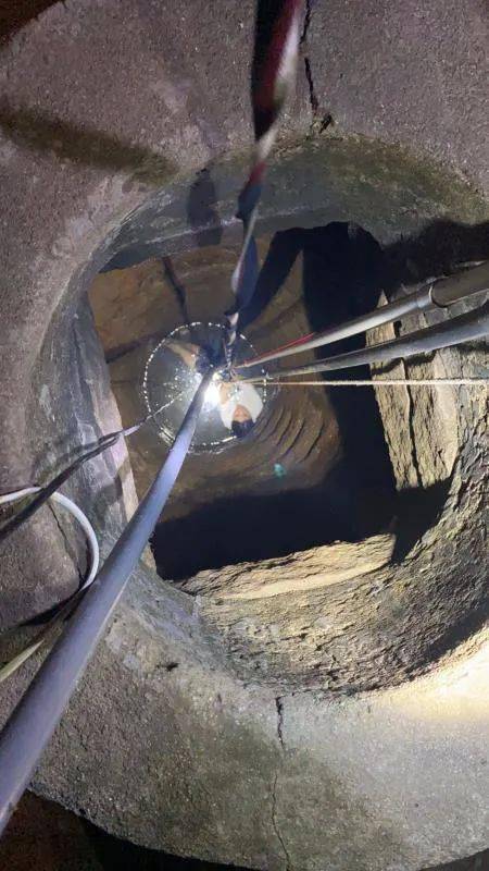 女子努力攀附井壁场景